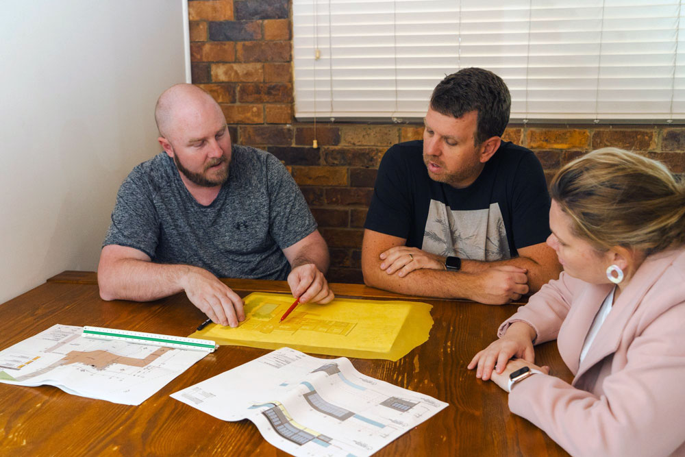 Nathan discussing design features & plans with clients at desk